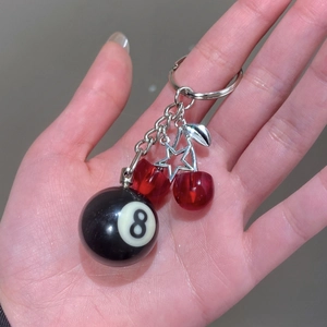 Close-up of cherry keychain featuring black number 8 billiard ball and silver star charm
