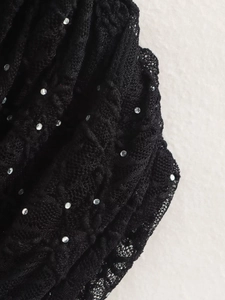 Détail du tissu en dentelle noire avec des strass étincelants sur un ensemble jupe et haut