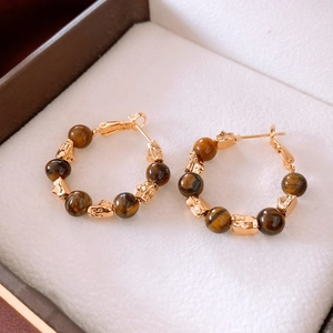 Macro shot of 18k gold plated hoop earrings with tiger eye beads in a jewelry gift box