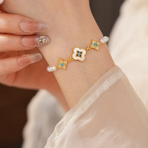 Dettaglio del bracciale a fiori placcato oro 18k con perle e turchese su un polsino