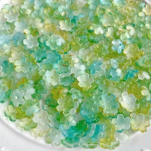 Close-up of translucent gradient flower beads with gold glitter for jewelry making