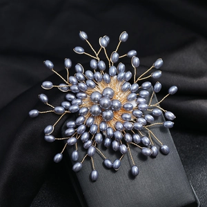 Detail of handmade snowflake brooch with grey pearls and golden wire on black velvet