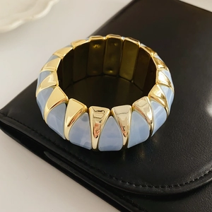 Close-up of retro elastic bracelet with light blue marble resin and golden triangle metal
