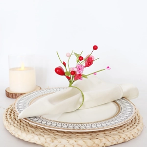 Christmas pine needle napkin ring with red and pink berries on a white cloth napkin