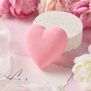 Close-up of heart-shaped pink bath bomb with floral accents and romantic decorative gift props