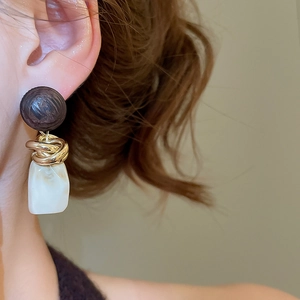 Gros plan de boucles d'oreilles géométriques en résine avec perles en bois et métal doré