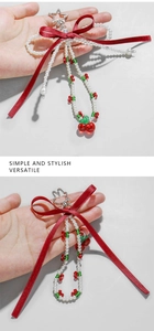 Detail of red ribbon bow keychain with white faux pearls and cherry beads on star clip