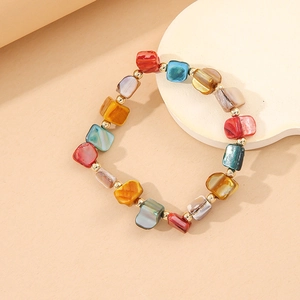 Colorful beaded bracelet with irregular stones and shell accents on a beige display