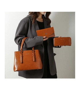 Three-piece brown oil-wax leather bag set shown on model featuring tote and clutches
