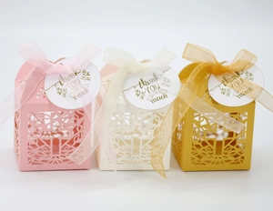 Detail van lasergesneden geschenkdozen in roze, wit en goud inclusief lint en labels