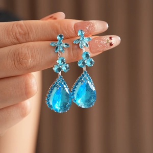 Gros plan d'une boucle d'oreille saphir bleu avec grappe florale et pierre en poire