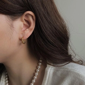 Detailed view of small gold twisted rope hoop earrings worn with elegant pearl necklace
