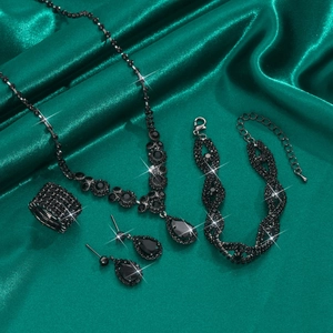 Detailed view of luxury black rhinestone bridal jewelry set on emerald satin background