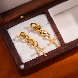 Cool gold cross dangle earrings with Cuban chain tassels displayed in a wooden jewelry box