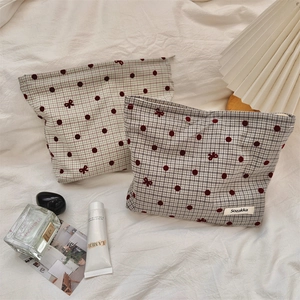 Close-up of quilted makeup bag with red polka dots and delicate bow embroidery details