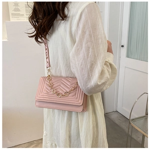 Detail of pink quilted shoulder bag with decorative floral gold chain and patterned strap