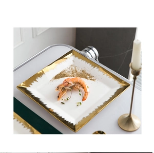 Detail of square ceramic plate with hand-painted gold rim featuring shrimp appetizer
