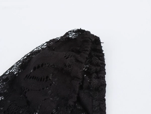 Dettaglio macro della cucitura in pizzo nero su abito a maniche lunghe con motivi
