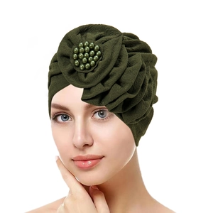 Detail of olive green turban hat featuring pleated fabric and handcrafted beaded 3D flower
