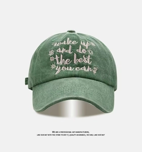 Detail of washed green vintage baseball cap with white embroidered inspirational text