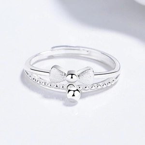 Macro detail of silver butterfly ring with matte finish bow and polished bead drop