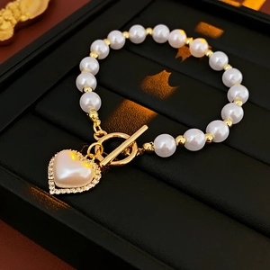 Dettaglio del bracciale di perle con ciondolo a cuore in cristallo e chiusura dorata OT