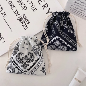 Detail of drawstring pouches with paisley patterns and thick cotton cords in black and white