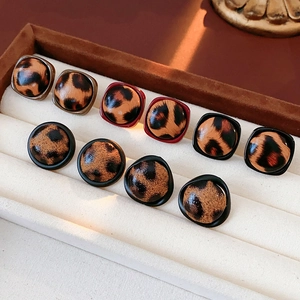 Détail de boucles d'oreilles léopard de formes carrées et rondes avec bordures métalliques