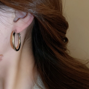 Close-up of minimalist silver hoop earring with polished finish on a model's ear