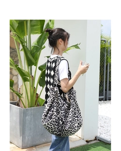 Detailed view of leopard print canvas tote bag styled with black and white knit vest