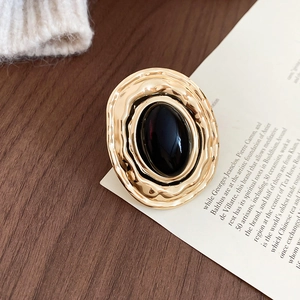 Dettaglio ravvicinato di un anello vintage dorato con una gemma acrilica nera ovale