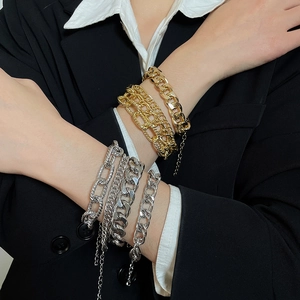 Detailed view of layered gold and silver chunky chain bracelets on a fashion model