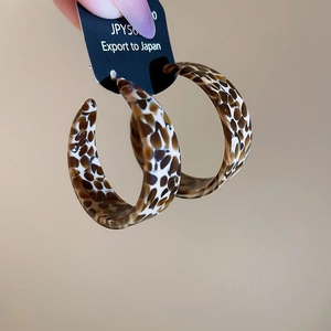 Detail of leopard print acetate C-shape hoop earrings with sterling silver needles