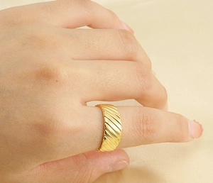 Detailed view of an 18k gold-plated ring with elegant diagonal grooved texture on hand