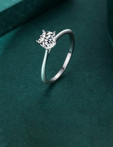 Close-up of sparkling zircon ring with classic four-prong setting on green background