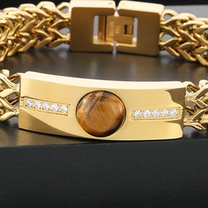 Macro view of gold stainless steel Cuban chain bracelet with tiger eye stone and cubic zirconia