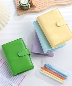 Flat lay of colorful A6 PU leather binder notebooks with magnetic buckle and pens