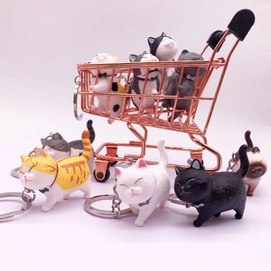 Detail of diverse miniature cat keychains in a mini shopping cart for collection