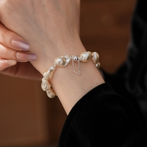 Macro detail of Baroque pearl bracelet with silver magnetic clasp and safety chain