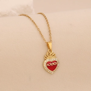 Close-up of golden sacred heart pendant with red enamel and sparkling zircon inlay
