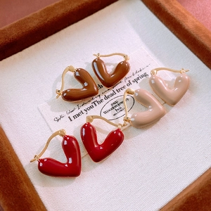 Detailed macro of heart enamel earrings in brown, beige, and red on velvet tray