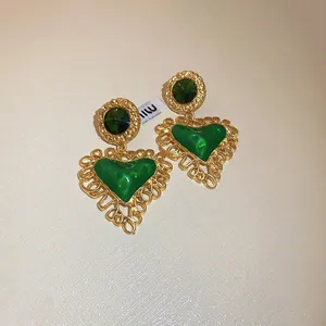 Detailed close-up of vintage gold heart earrings with green enamel and rhinestone accents