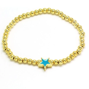 Detailed macro of golden beaded bracelet with blue enamel star pendant on white backdrop