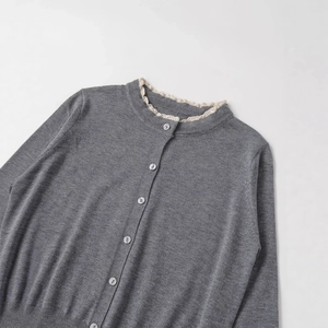 Women's minimalist grey knit cardigan with white lace trim collar and pearl buttons
