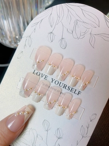 Detail of pink and creamy white French press-on nails with elegant pearls and gold beads