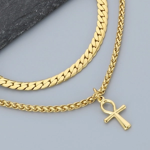 Close-up of golden double layer necklace with Ankh cross pendant and Cuban chain links