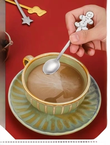 Detail of silver stainless steel gingerbread man spoon being held over a coffee cup