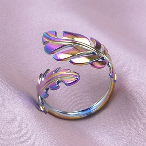 Close-up of iridescent leaf pattern stainless steel ring on soft purple satin fabric