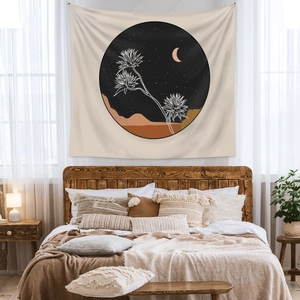 Detail of bohemian wall tapestry with moon and mountain print over a bed in a bedroom