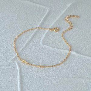 Detail of s925 silver gold bracelet featuring a cross element and sparkling cubic zirconia